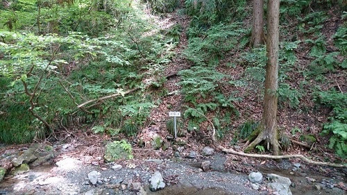 小川の向こう側に露天掘り跡を示す看板